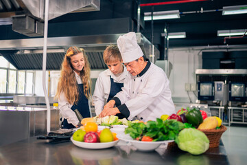 A group of male and female students are learning to cook in the kitchen of a cooking school.