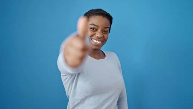 African american woman smiling with thumbs up over isolated blue background
