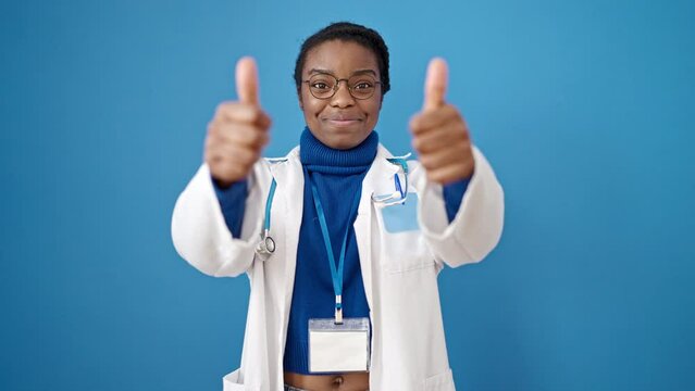 African american woman doctor doing thumbs up over isolated blue background