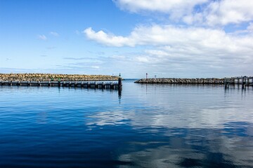 Scenic view of a pier on a tranquil sea reflecting cloudy blue sky in Australia