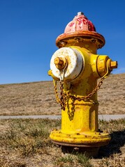 Vertical closeup shot of a rusty yellow fire hydrant on a rural field