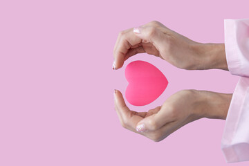 Heart in Doctor's hands on pink background. A Doctor's hand protecting and reassures...