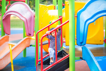 Little asian boy playing in outdoor playground slider and crimbing