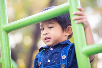 Adorable asian 2 - 3 year boy climbing in playground