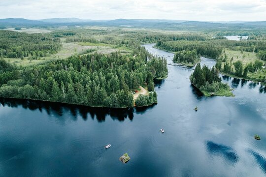 Aerial shot of a turquoise lake,a forest with dense trees in the background in Bjorbo Dalarna Sweden