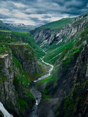 Aerial view of a gorge with a river between rocky mountain slopes, and a waterfall in the background