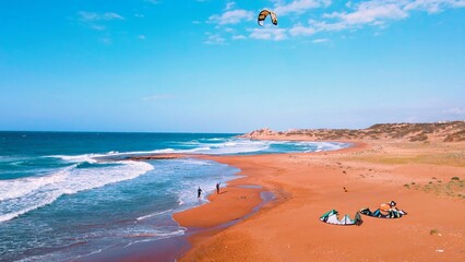 A group of people kite surfing at Alagadi Beach in Kyrenia, North Cyprus on sunny day with clear sky - obrazy, fototapety, plakaty