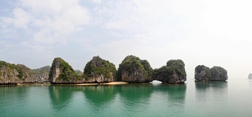 Fototapeta na wymiar Panoramic shot of the rocks reflected in the water in Halong Bay, Vietnam