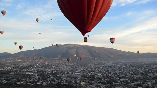 A large red hot air balloon soars over the city of Teotihuacan, Mexico. The city is home to the ancient Pyramids of the Moon and Sun, which are comparable in size to the pyramids of Egypt.