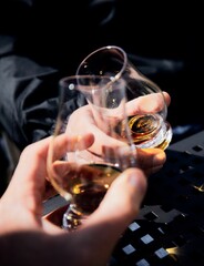 Close-up shot of hands toasting with a good old Brandy