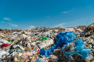 A pile of garbage in a landfill against a blue sky