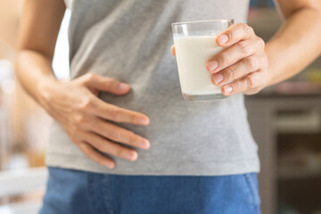 Pain, suffering asian young woman having a stomachache, abdominal pain or digestive, hand in...