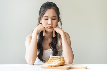 Gluten allergy, asian young woman, girl refusing to eat, looking at bread slice on plate in...