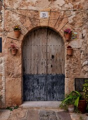 Fototapeta na wymiar Stone medieval arch door of Valldemossa village with pot plants in Mallorca, Spain, vertical shot