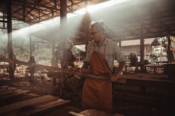 Fototapeta na wymiar Young male carpenter with an apron working make furniture at a warehouse