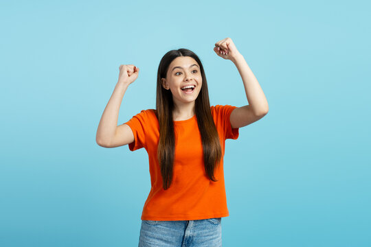 Portrait of beautiful teenage girl showing winner gesture isolated on blue background