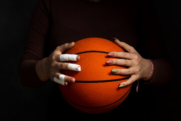 Concept Women's sport. Hands hold the ball. One hand in tapes. Second hand with manicure