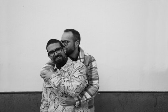 A young couple of gay men. Marriage is happy as one man grabs the other from behind and they join hands. Homosexual rights concept. Black and white photo