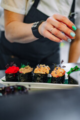 professional chef's hands making gunkan sushi roll in a restaurant kitchen