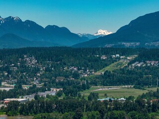 Fototapeta na wymiar Drone shot of Coquitlam cityscape with greenery and mountain in the background