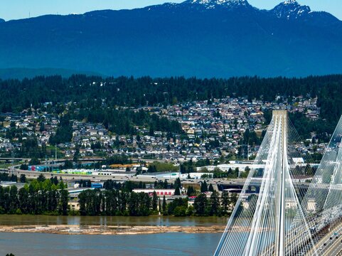 Drone shot of Coquitlam cityscape with Port Mann Bridge, river and mountain in the background