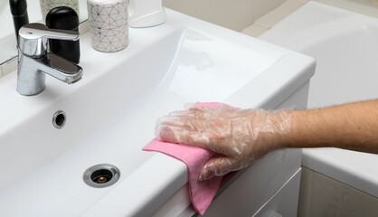 Closeup of human hand wearing disposable plastic gloves and cleaning sink