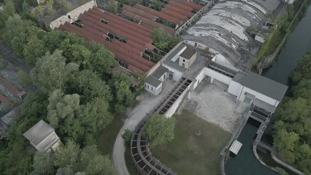 Drone footage of abandoned factory surrounded by lush green trees in Pordenone, Italy