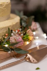 Vertical closeup shot of decorative beautiful flowers near a cream wedding cake