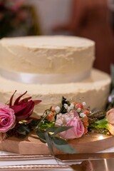 Vertical shot of decorative beautiful flowers near a cream wedding cake