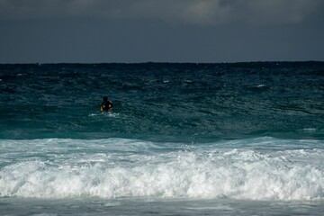 Body boarder surfing on a gloomy day with big foamy waves.\nSuitable for background photos.