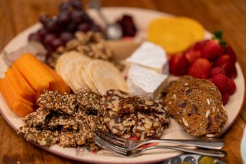 Closeup shot of a cheese plate with brie cheese, berries, crackers, etc., on the table