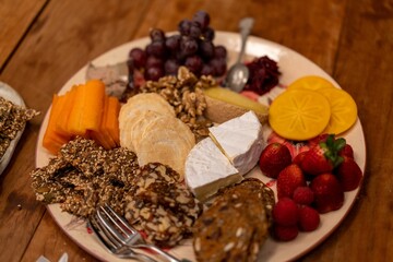 Closeup shot of a cheese plate with brie cheese, berries, crackers, etc., on the table