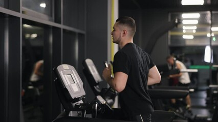Fitness equipment, Gym motivation, Gym treadmill. The gym enthusiast is running at a moderate pace on the treadmill.