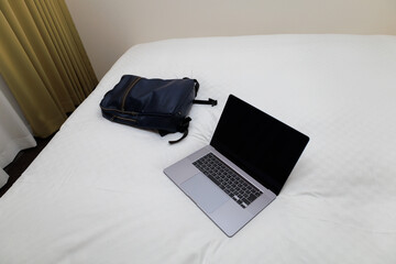 	ベッドに置いたノートパソコンとリュック