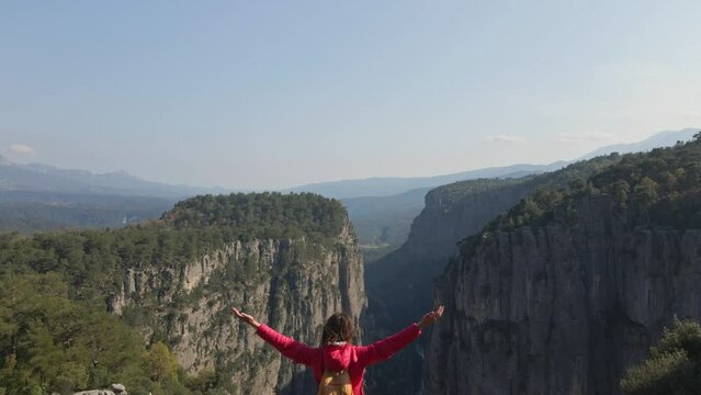 Aerial View point of Tazy Canyon. girl standing and admiring stunning scenery in mountains. Tourist woman hiker in red jacket on cliff against backdrop of gorge. Amazing Tazi Canyon, Turkey.