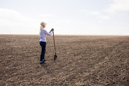 A woman farmer stands on his parched meadow. Rising temperatures and too little rain. Drought concept.