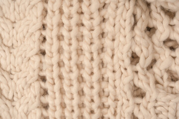 A fragment of beige knitted fabric, knitted from white sheep wool.
