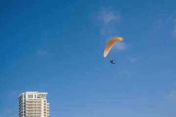 paragliding. extreme sport. Paraglider silhouette flying in the blue sky over the city.