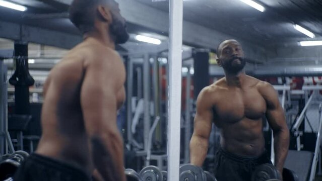 Fit African American male grabs dumbbells off rack