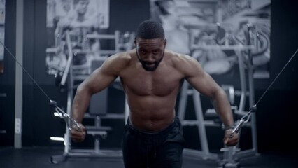 Muscular African American doing cable chest flys Front on