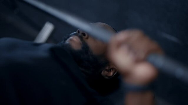 A black man bench-pressing weight in the gym