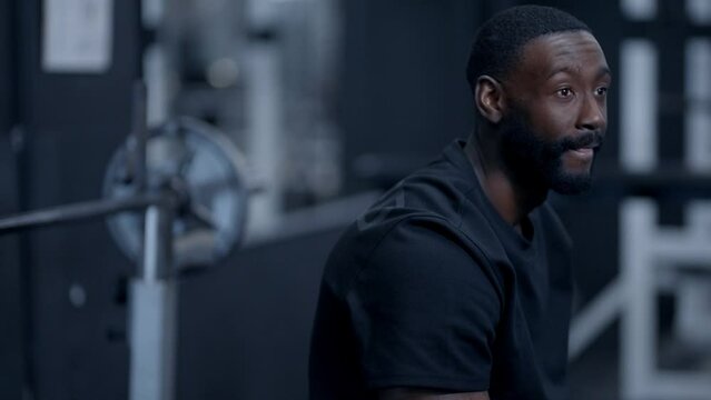 An African American man resting between sets in gym