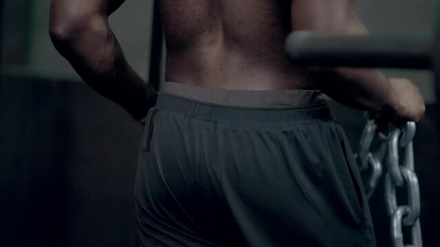 African American man placing chain around neck for weighted dips exercise