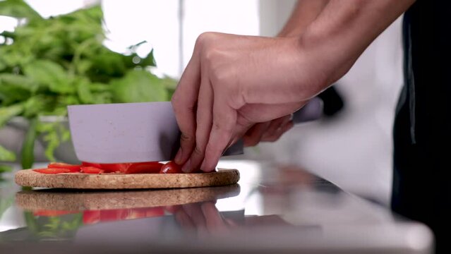 4K closeup hands working in kitchen, junior chef chopping vegetables tomatoes on table in restaurant, staff man working in cooking uniform, multi-task in small business owner lifestyles concept