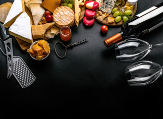 Different kinds of cheese served with wine bottle, glasses and grape for gourmet nutrition. Organic parmesan and brie set with alcohol composition