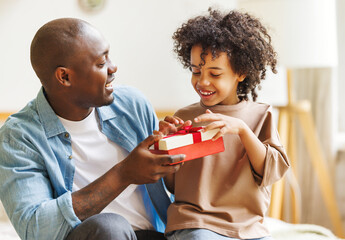 Happy Fathers day. African american kid son giving  gift box to dad for holiday at home