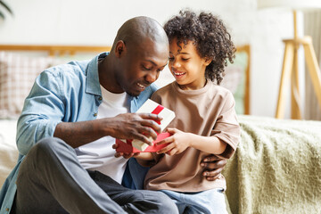 Happy Fathers day. African american kid son giving  gift box to dad for holiday at home
