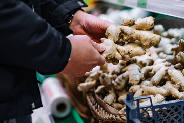 man hand holding ginger root in grocery store in supermarket