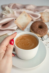 Close-up of a cup of coffee held by a woman's hand.