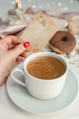 Close-up of a cup of coffee held by a woman's hand.